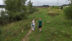 Young couple jogging near pond on summer day, surrounded by lush greenery. Outdoor activity highlights fitness and connection with nature. countryside and active lifestyle.  - Powered by Shutterstock - Get 15% off with code: PIKWIZARD15