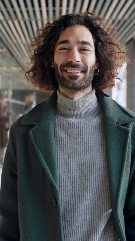 Young hispanic professional man with beard and long hair walking in the office workplace. Inspired creative business person with successful career 
