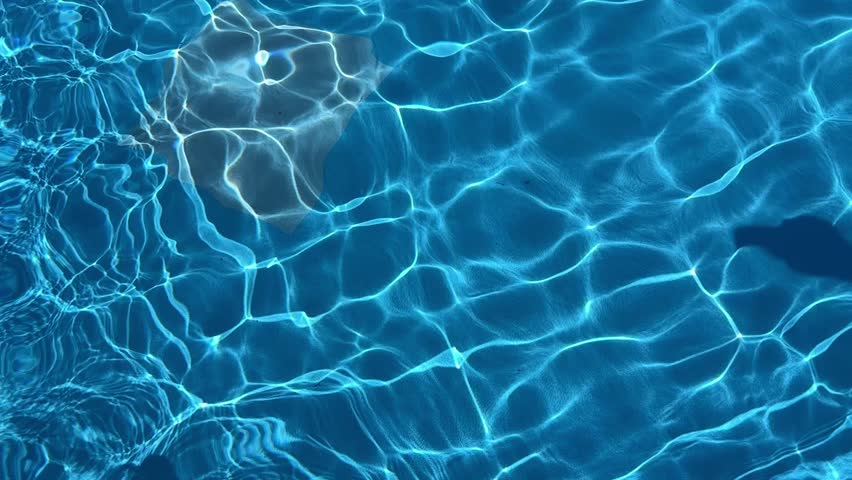 The Beautiful Blue Water Of The Swimming Pool Reflects Sunlight, Creating Sparkling Ripples. The Clear, Caustic Texture Of The Water Adds A Stunning Visual, Captured In Slow Motion.