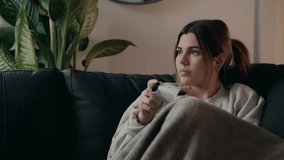 A Young Woman, Holding a Controller and Sitting Comfortably on the Couch, is Fully Immersed in Her Game - Close Up - Powered by Shutterstock - Get 15% off with code: PIKWIZARD15