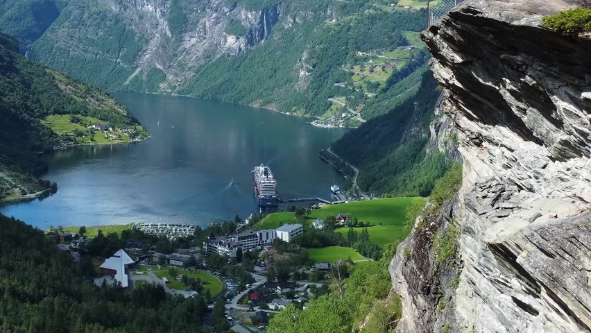 Rocky mountain and small township with cruise ship in Norway fjord, aerial view