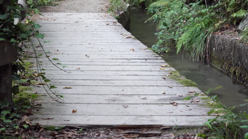A hiker walking along a short footbridge near a man-made irrigation canal. this is part of a hiking trail.