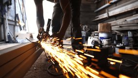 Male hands of young craftsman cuts iron using electric grind wheel at workshop. Arms of professional repairman sawing metal construction with a circular saw at garage or workplace. Slow motion - Powered by Shutterstock - Get 15% off with code: PIKWIZARD15