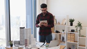 Indian male architect in modern office using digital tablet to develop city project with model buildings, emphasizing creativity and concentration. - Powered by Shutterstock - Get 15% off with code: PIKWIZARD15