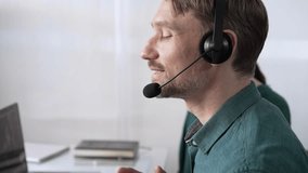 Focused male call center operator in green casual shirt is assisting clients online, providing customer support and answering inquiries. Call center concept - Powered by Shutterstock - Get 15% off with code: PIKWIZARD15