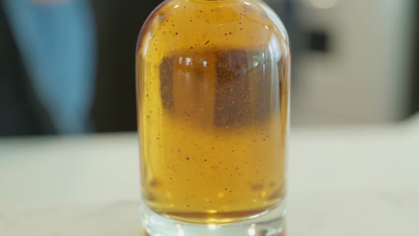 Close up shot of bottle being filled with vanilla extract.