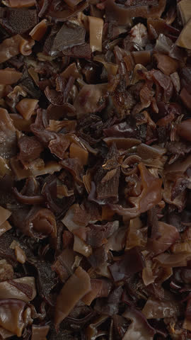 Dried, hydrated and chopped mun mushrooms as an abstract food pattern. An ingredient of Chinese cuisine. Table spin. Vertical video.