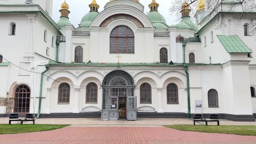 Camera movement reveals the saint Sophia Cathedral in Kyiv, Ukraine, under a grey, cloudy sky. The majestic architecture showcases its iconic golden dome and historical significance
