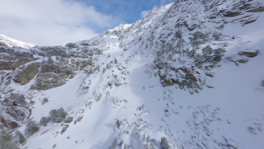 Drone flying over snowy mountainside of Pyrenees near Incles Valley, Andorra. Aerial fpv
