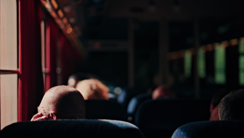 People sitting in a moving train with sunlight peaking through the windows