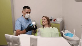 consult dentist, patient education, dental assistance. While holding dental model and tools, male dentist engages in discussion about treatment with female patient in dentist's chair, exuding calm - Powered by Shutterstock - Get 15% off with code: PIKWIZARD15