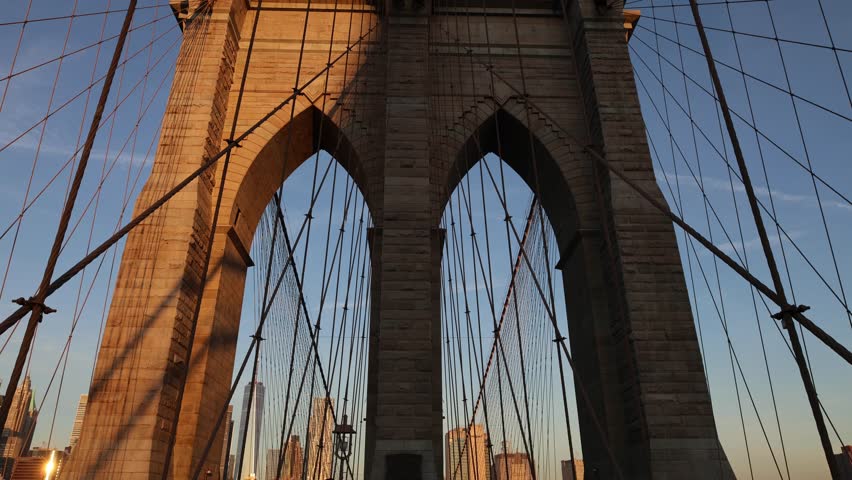 panning up at the brooklyn bridge at sunrise (beautiful suspension overpass pedestrian walkway between manhattan and borough new york city) nyc landmark travel tourism destination