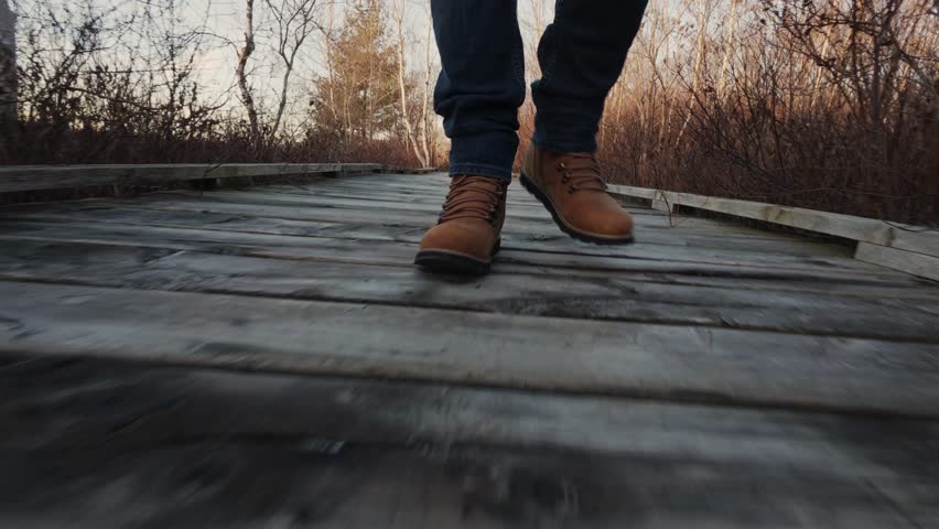 Hiking Boots Walking On A Wooden Suspension Bridge Over A Majestic Wild Mountain Lake. This Footage Captures The Essence Of Epic Outdoor Exploration And Hiking Adventure.