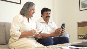 Middle age mature man and woman couple using smart phone and drinking tea or coffee at home. Senior couple use cellphone. Social media. Wireless technology. Online internet user.  - Powered by Shutterstock - Get 15% off with code: PIKWIZARD15
