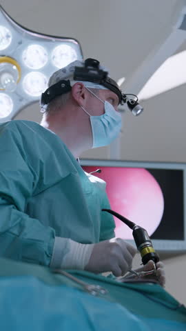 Vertical Screen: Surgeos performing a medical procedure in a modern operating room, focused on minimally invasive surgery using advanced equipment. Concept of healthcare, and innovation.