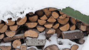Snow falls in slow motion against the backdrop of a pile of firewood. Snowy weather. Stack of firewood in winter. Slowly falling snowflakes. A magical sight. Natural beauty and tranquility - Powered by Shutterstock - Get 15% off with code: PIKWIZARD15