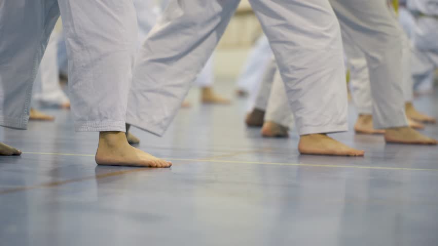 Karate class practicing coordinated stances in white uniforms