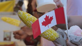 Canada Surrey Hot corn and Canada flag sprinkle salt on the corn Canada Day Families, people dressed in red, walk in the square on a holiday weekend - Powered by Shutterstock - Get 15% off with code: PIKWIZARD15
