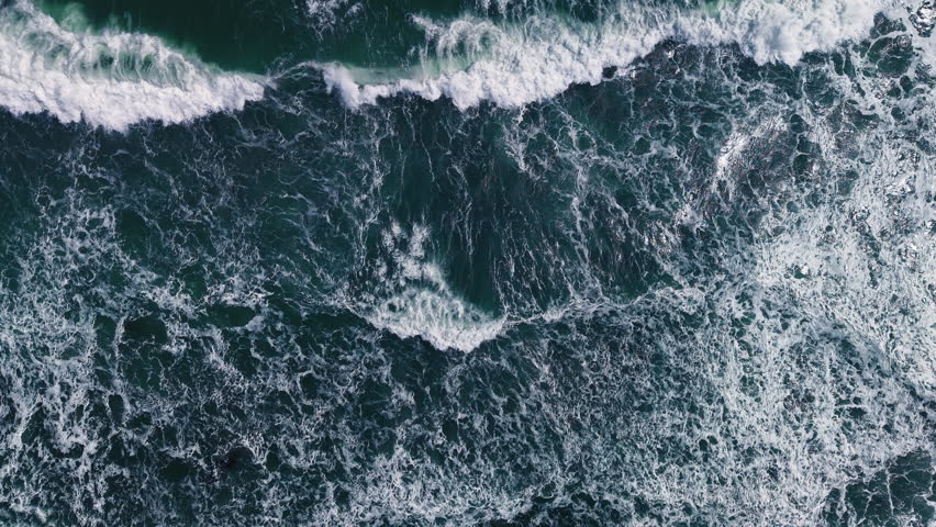 Aerial view, top view of sea waves on beach sand. Royalty high-quality free best stock of turquoise colored breaking wave seascape on the beach. Wave crashing, splash