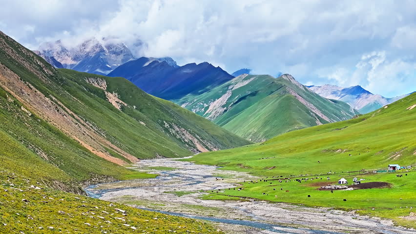 Curved river and green grassland with mountain natural landscape in Xinjiang. Beautiful scenery along the Duku Highway in China.