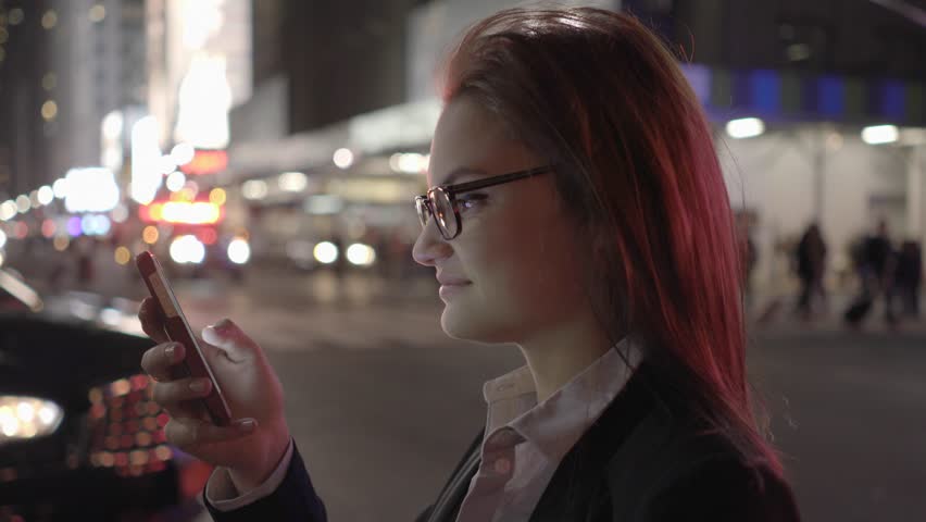 A Young Woman Navigates City Streets with her Smart Phone