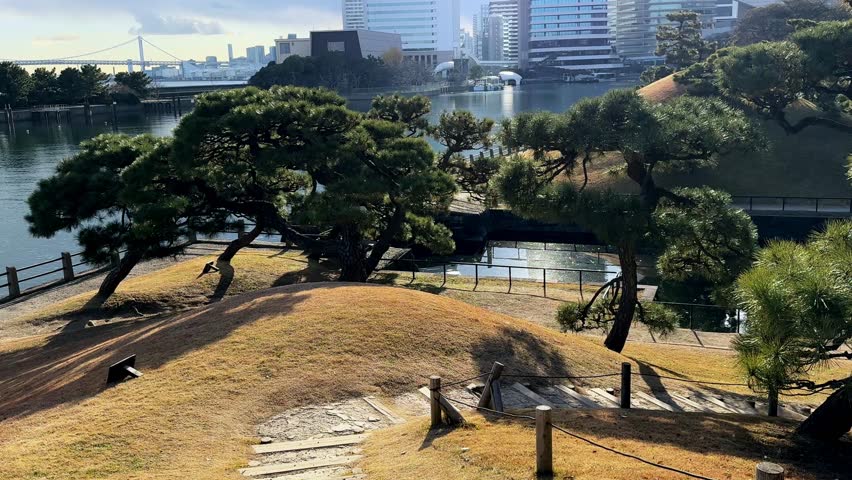 A serene Japanese garden with pine trees, city skyline, and calm water reflecting nature
