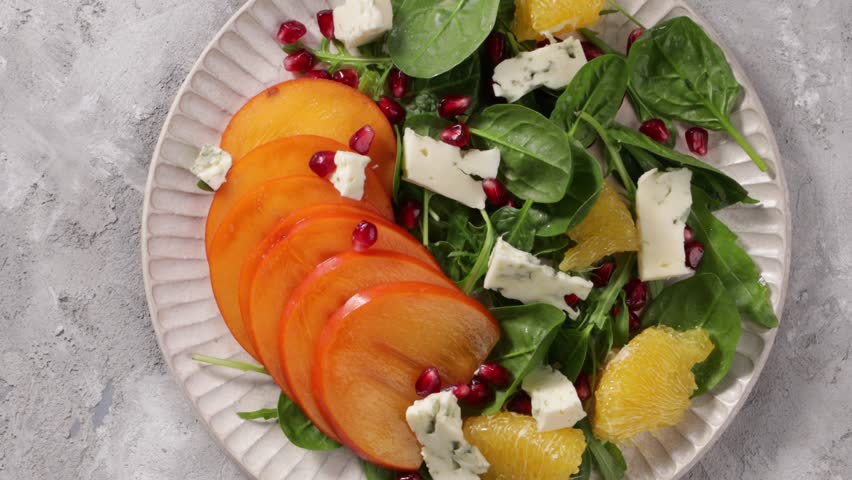 top view of persimmon salad with orange and cheese on plate