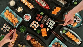 Top View of Various Kind of Sushi Pieces with Camera Motion. Fresh Japanese Sushi, Asian Cuisine Concept. People it Picking up. Placed on Black Stone Table.  Camera Placed on Motion Control System. - Powered by Shutterstock - Get 15% off with code: PIKWIZARD15