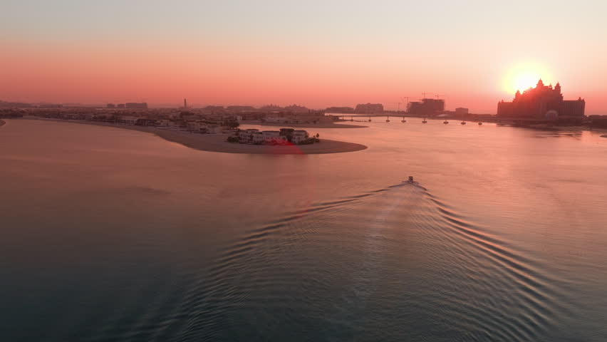 The breathtaking aerial view of Palm Jumeirah in the UAE, captured beautifully at sunset, showcases its iconic palm treelike shape and the stunning skyline that surrounds it