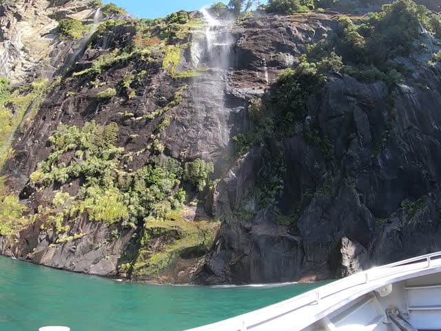 Cruise ship sailing through The Sounds, Mitre Peak and waterfalls at Milford Sound, Fiordland National Park. New Zealand tourist attraction. 