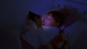 Young girl in bed using a smartphone at night, illuminated by its blue light. Concept of screen addiction, internet dangers, and the impact of excessive device usage on children. - Powered by Shutterstock - Get 15% off with code: PIKWIZARD15