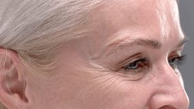 Close up portrait: blue eye of an old blonde woman with large wrinkles. Smile of a senior female, elderly retired beauty care. Product for skincare with natural anti-aging cosmetics, mascara eyelashes - Powered by Shutterstock - Get 15% off with code: PIKWIZARD15