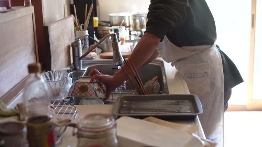 Image of a woman washing cooking utensils
