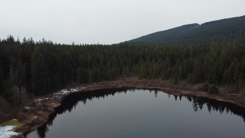 Nature’s calm revealed: flying over a lake and mountains on a cloudy day
