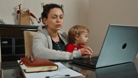 Mother multitasking with computer while comforting her crying toddler - Powered by Shutterstock - Get 15% off with code: PIKWIZARD15