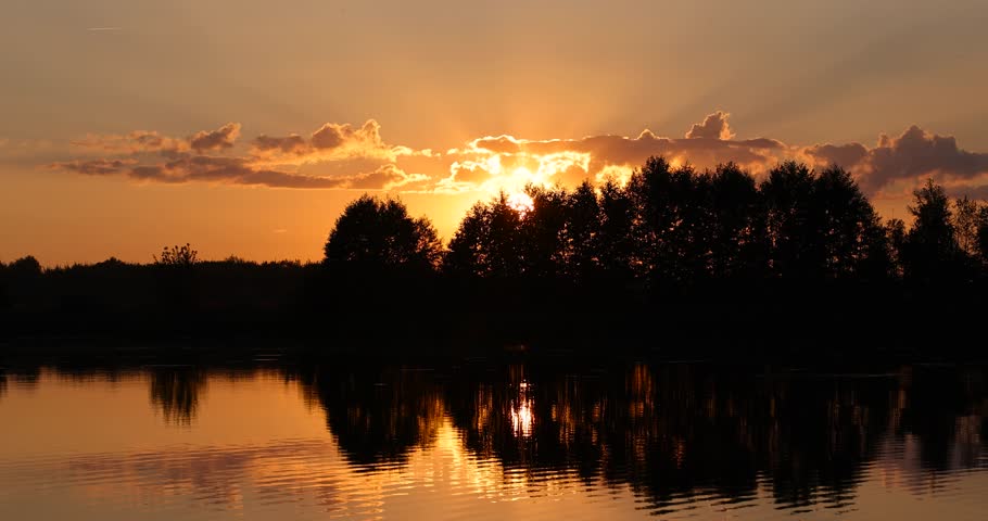 orange sky at sunset on the river with a forest on the shore, a beautiful orange sunset on the river in summer is reflected in the water