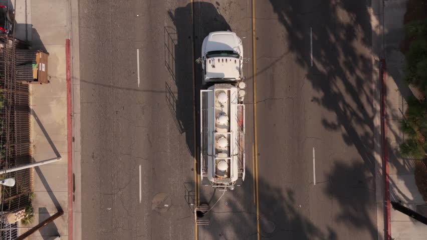 An Aerial View Capturing a Tanker Truck Positioned Above a Drain on a Busy Road during Peak Traffic Hours