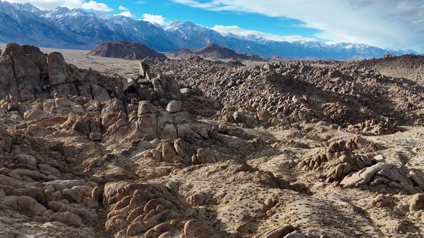 The Alabama Hills, located near Lone Pine, California, offer a stunning contrast of rugged rock formations and the backdrop of the majestic Sierra Nevada mountains. Drone. 
