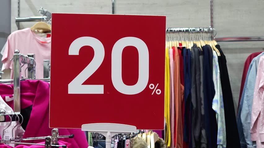 Red discount sign with 20% text in a clothing store. Retail promotion and sales concept. Discount signs