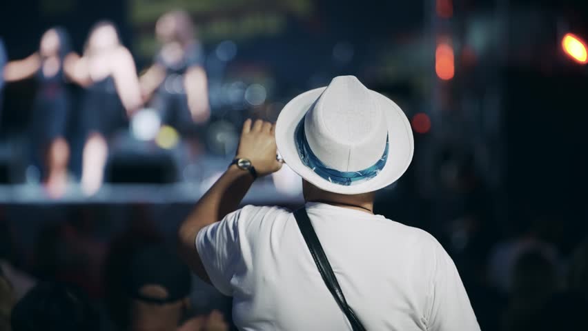 Unrecognizable music fan taking photos with his phone on open air music concert in summertime