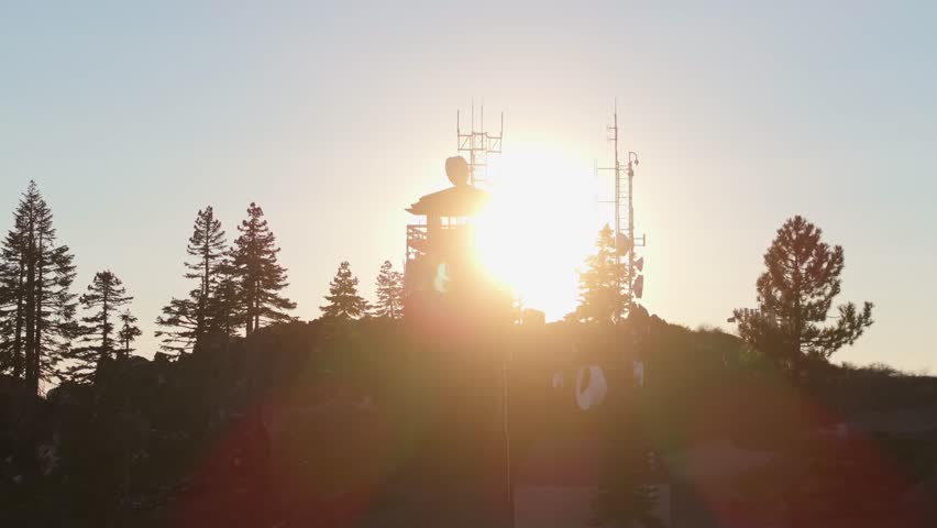 Sunset view behind Mt. Hough Fire Lookout surrounded by trees and communication towers