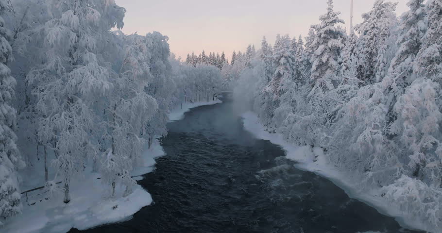 Aerial view flying low over the Kitkajoki river, winter morning in North Finland