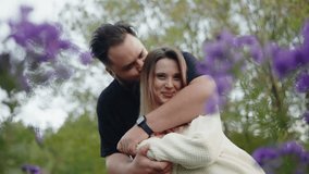 A romantic couple embraces in a tranquil garden setting, surrounded by blooming purple flowers, showcasing love and affection. Romantic Couple Embracing in a Blooming Garden, Love and Affection - Powered by Shutterstock - Get 15% off with code: PIKWIZARD15
