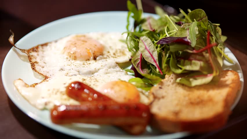 Cook British Breakfast. Sausage And Eggs On Keto Dieting. Traditional English Breakfast Fry Eggs Yolk ,Sausage Crisp Bread Toast. Tasty Nourishing Balanced Breakfast Pan-fried Eggs At Ketogenic Diet
