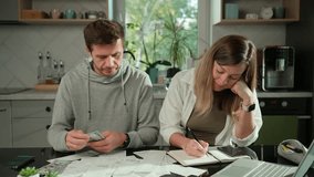 Worried couple planning family budget at home. Man and woman counting money and checking utility bills and receipts at kitchen table. Concept of rising costs in households - Powered by Shutterstock - Get 15% off with code: PIKWIZARD15