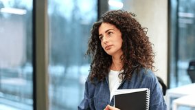 Friendly business woman with curly hair smiles and talks to colleague in modern office space near large window. - Powered by Shutterstock - Get 15% off with code: PIKWIZARD15