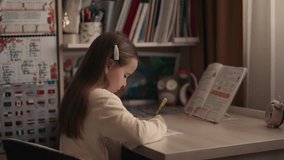 Young girl writing in notebook. Child doing homework or homeschooling. Girl studying at desk. - Powered by Shutterstock - Get 15% off with code: PIKWIZARD15