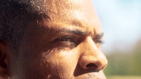 Close-up of focused African American athlete sweating after an intense outdoor workout. Determined male catching his breath under a clear, blue, sky while recovering from physical exertion - Powered by Shutterstock - Get 15% off with code: PIKWIZARD15