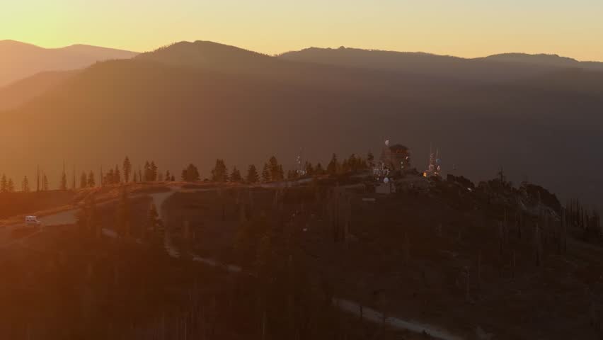 Mountain landscape at sunset with a winding road, trees, and warm golden light at Mt. Hough CA