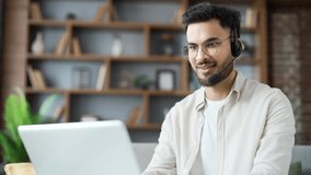 Confident businessman in headset talking on a video call using laptop sitting in home office. Entrepreneur has online business meeting with partner. The teacher speaks remotely with students. Close up - Powered by Shutterstock - Get 15% off with code: PIKWIZARD15